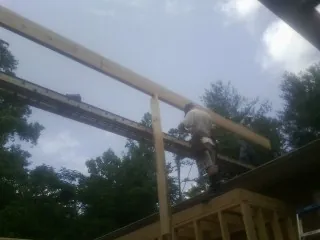 Carpenter setting a ridge beam over a new addition frame — Ice Dam Removal by Roofing Brothers in Wolverton