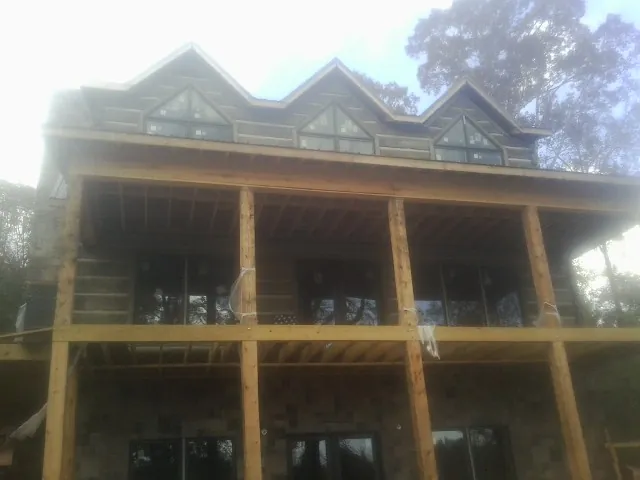 Dormers and porch framing on a large log home under construction — Roof Coating work by our crew in Wolverton