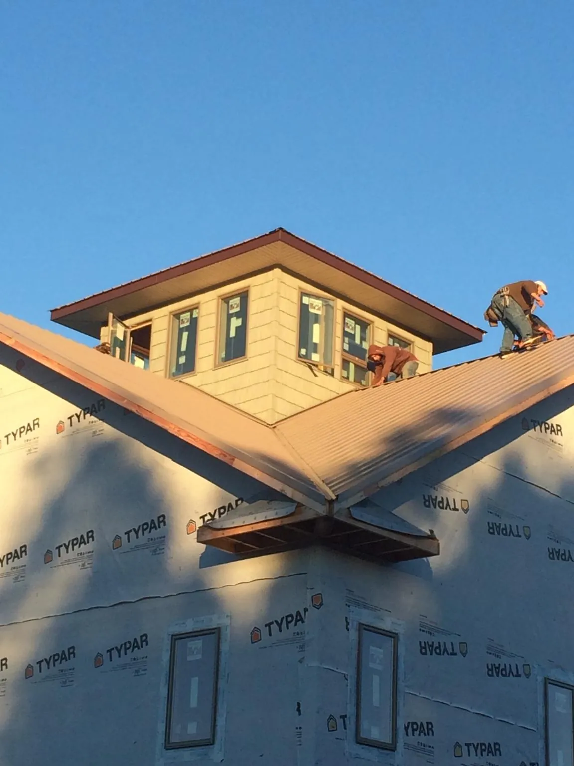 Roofers working around a rooftop cupola on a new metal roof at sunset — Roof Waterproofing in Wolverton by Roofing Brothers